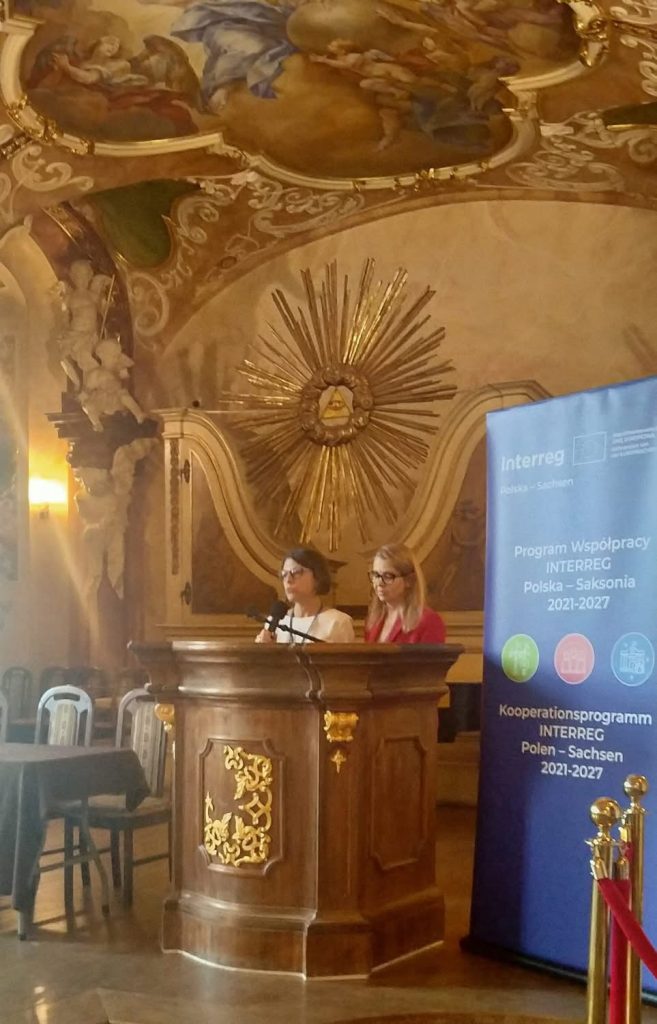 2 kobiety przemawiają w bogato zdobionej sali