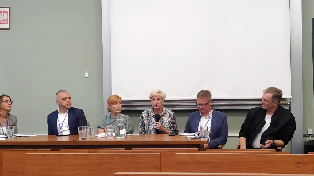 osoby przy biurku w trakcie konferencji